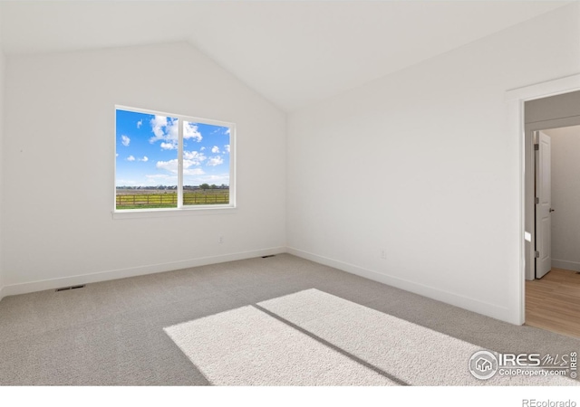 unfurnished room with light colored carpet and vaulted ceiling