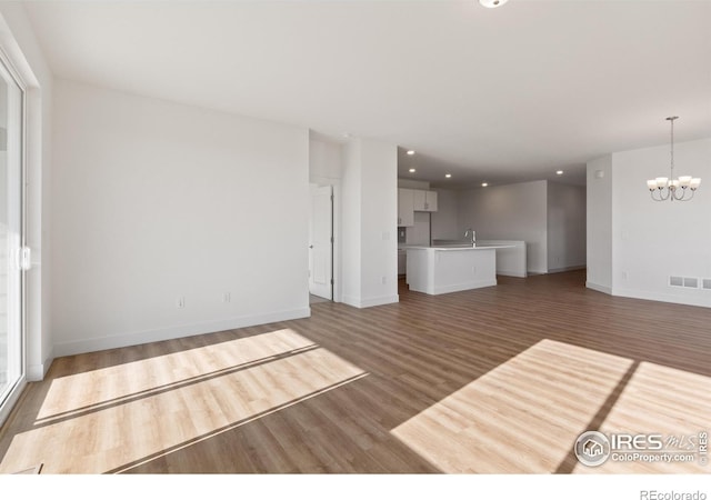 unfurnished living room with dark wood-type flooring and an inviting chandelier