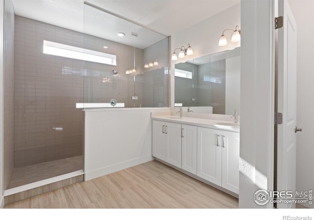 bathroom featuring hardwood / wood-style flooring, vanity, and a tile shower