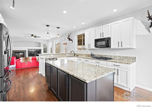 kitchen with hanging light fixtures, white cabinets, stainless steel fridge, dark hardwood / wood-style flooring, and gas stovetop