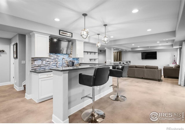 kitchen featuring decorative light fixtures, white cabinetry, a breakfast bar area, backsplash, and a center island