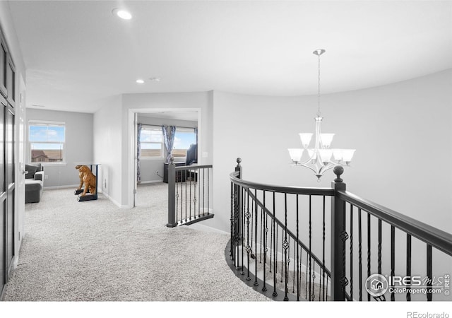 corridor with a notable chandelier and light colored carpet