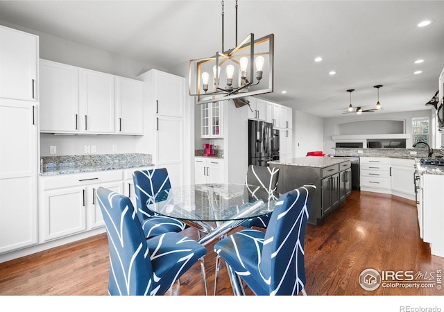 dining area with ceiling fan with notable chandelier and dark wood-type flooring