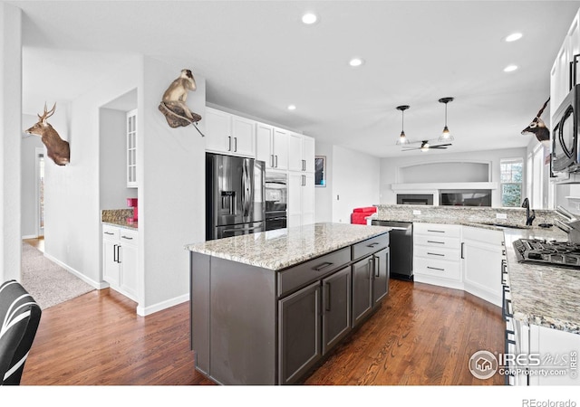 kitchen featuring dark wood-type flooring, stainless steel appliances, white cabinetry, and light stone counters