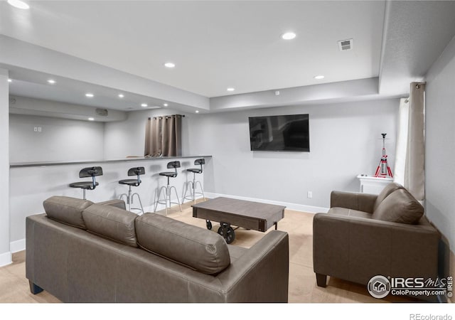 living room with a tray ceiling and bar