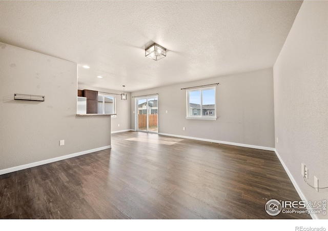 unfurnished living room with a textured ceiling and dark wood-type flooring