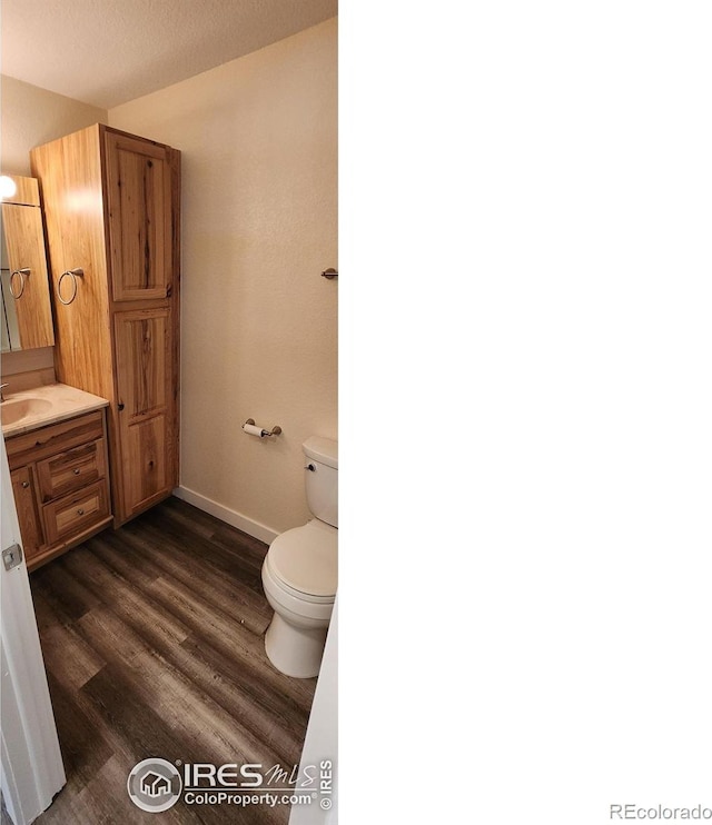 bathroom featuring wood-type flooring, vanity, and toilet