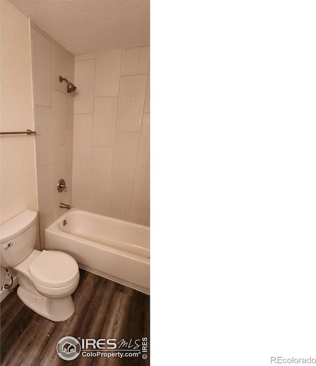 bathroom with hardwood / wood-style flooring,  shower combination, toilet, and a textured ceiling