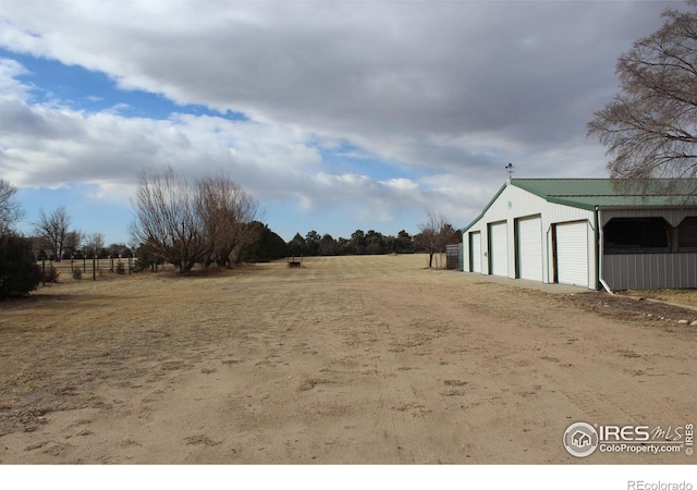 view of yard with a rural view, a garage, and an outdoor structure