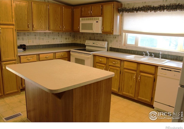 kitchen featuring white appliances, a center island, tasteful backsplash, and sink