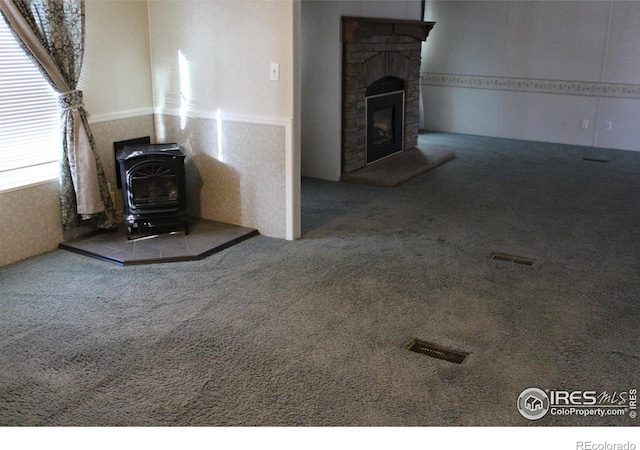 unfurnished living room with carpet and a wood stove