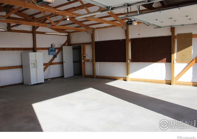 garage with a garage door opener and white refrigerator with ice dispenser