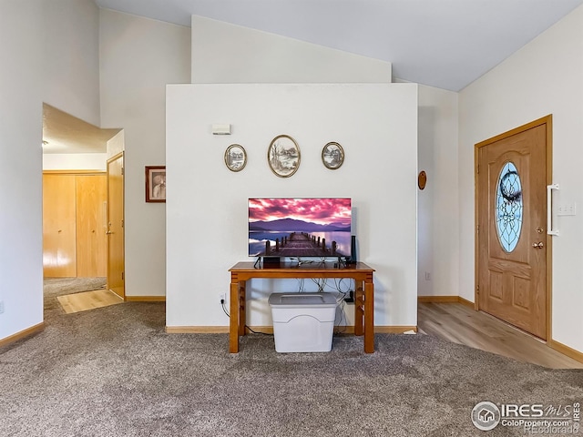 foyer entrance featuring carpet floors and vaulted ceiling