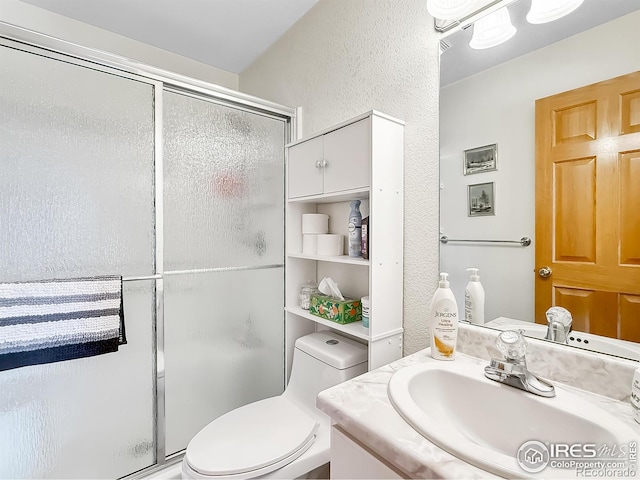 bathroom with vanity, toilet, and a shower with door