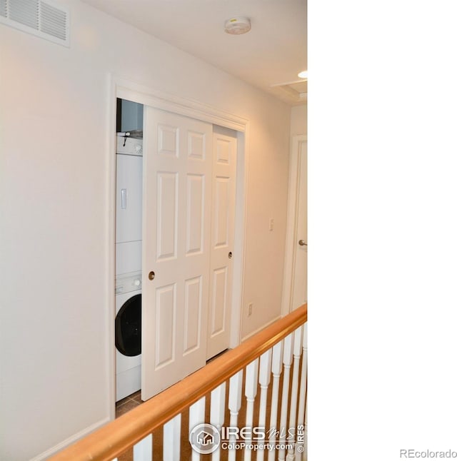 corridor with stacked washer and clothes dryer