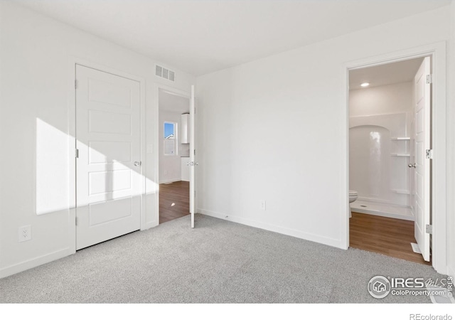 unfurnished bedroom with carpet flooring and connected bathroom