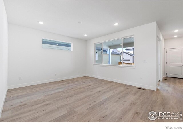 empty room featuring a wall mounted air conditioner and light hardwood / wood-style flooring