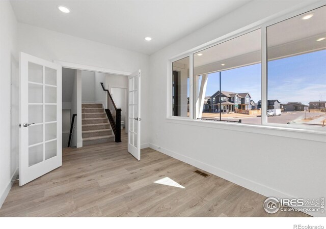 empty room with light hardwood / wood-style flooring and french doors