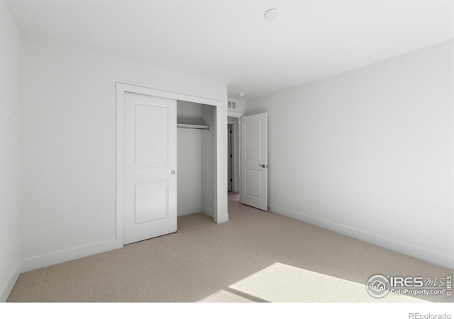 unfurnished bedroom featuring light carpet and a closet