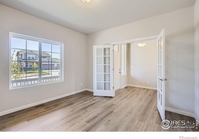 empty room featuring french doors and light hardwood / wood-style floors