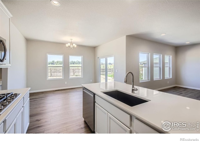 kitchen with sink, stainless steel appliances, dark hardwood / wood-style floors, decorative light fixtures, and white cabinets