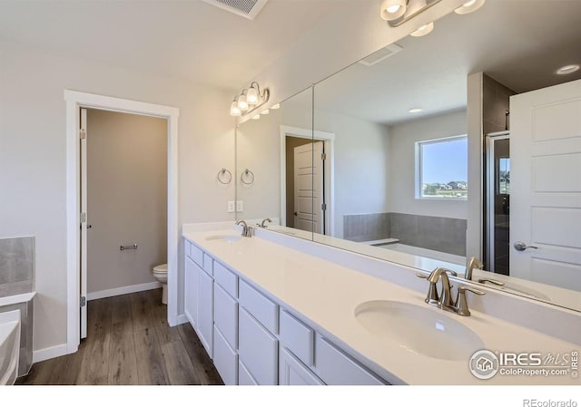 bathroom with wood-type flooring, vanity, toilet, and a bathing tub