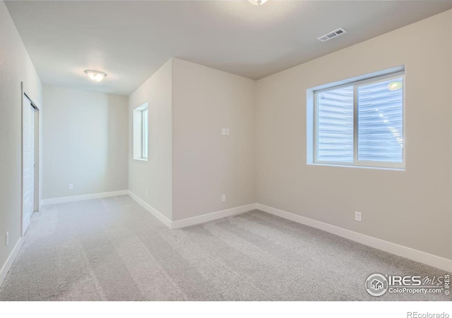 spare room featuring light carpet and a wealth of natural light