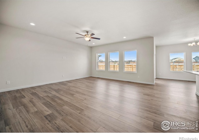 spare room with wood-type flooring and ceiling fan with notable chandelier