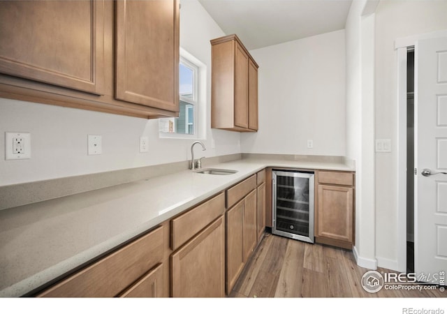 kitchen featuring wine cooler, sink, and light wood-type flooring