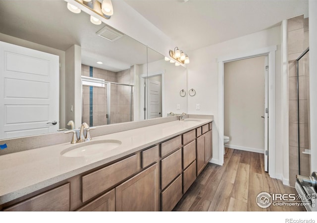 bathroom featuring hardwood / wood-style flooring, walk in shower, vanity, and toilet