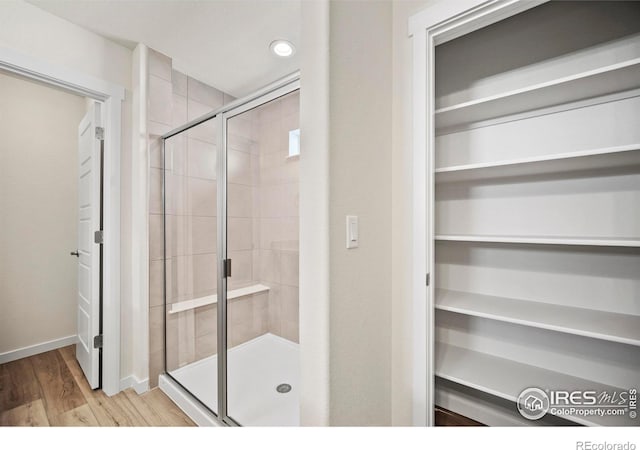 bathroom with a shower with door and wood-type flooring