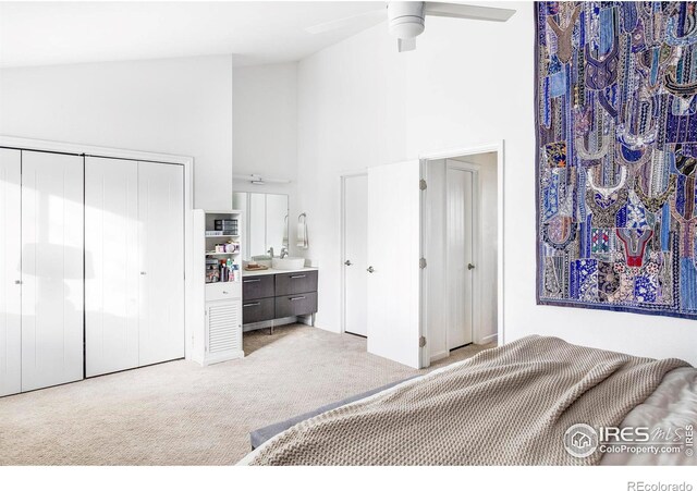 carpeted bedroom with ceiling fan, a closet, and high vaulted ceiling