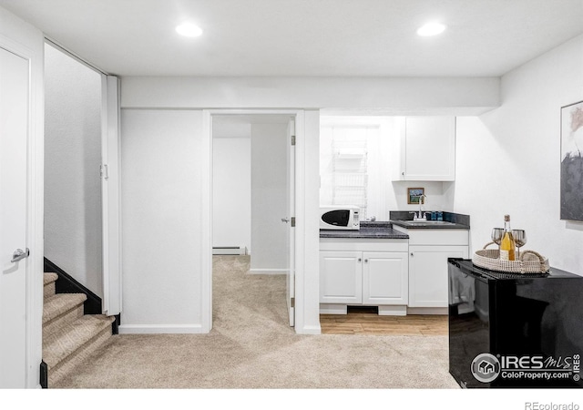 kitchen featuring light carpet, white cabinets, beverage cooler, and a baseboard heating unit