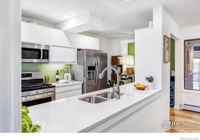 kitchen with tasteful backsplash, stainless steel appliances, sink, a baseboard radiator, and white cabinets