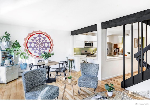 living room featuring light hardwood / wood-style floors, a baseboard heating unit, and sink