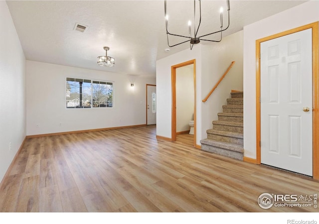 unfurnished living room with light hardwood / wood-style flooring and a notable chandelier