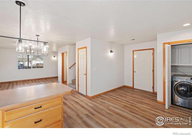 kitchen with pendant lighting, light brown cabinets, light hardwood / wood-style flooring, a textured ceiling, and washer / clothes dryer