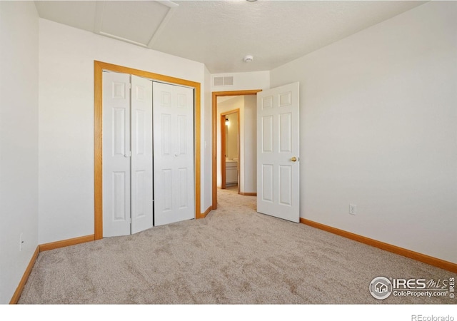 unfurnished bedroom with light carpet and a closet