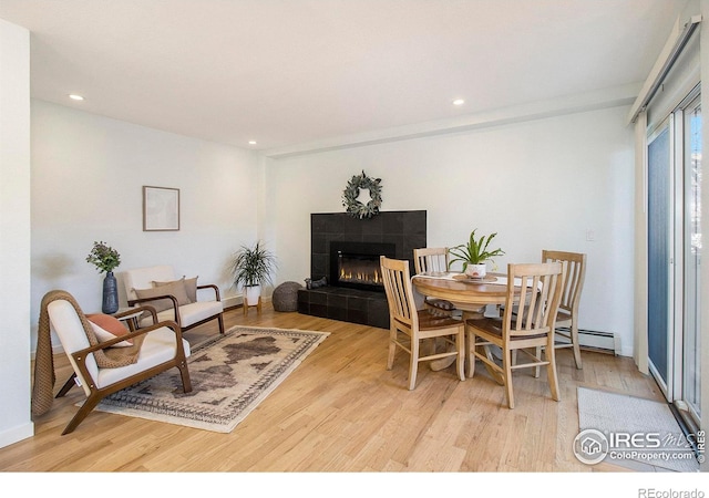 dining space with a fireplace, light hardwood / wood-style floors, and a baseboard radiator