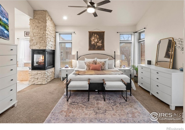 bedroom featuring multiple windows, vaulted ceiling, light carpet, and a fireplace