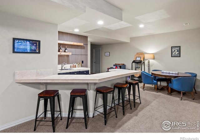 kitchen with sink, a breakfast bar, light colored carpet, and kitchen peninsula