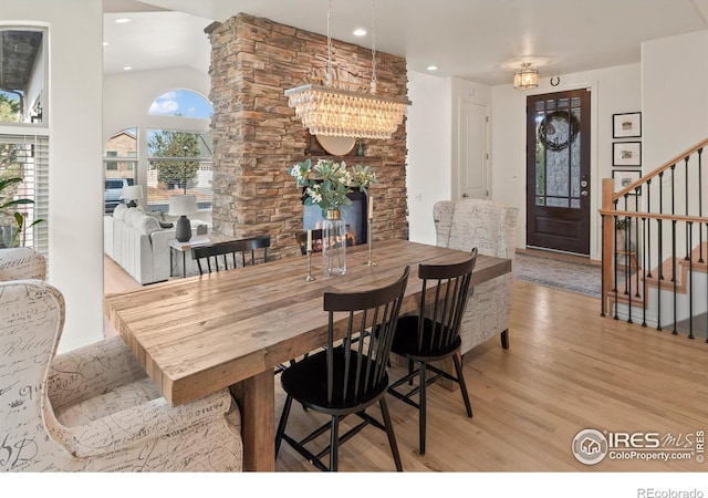 dining space featuring an inviting chandelier, a fireplace, and light hardwood / wood-style floors