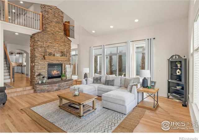 living room featuring hardwood / wood-style floors, a stone fireplace, and high vaulted ceiling