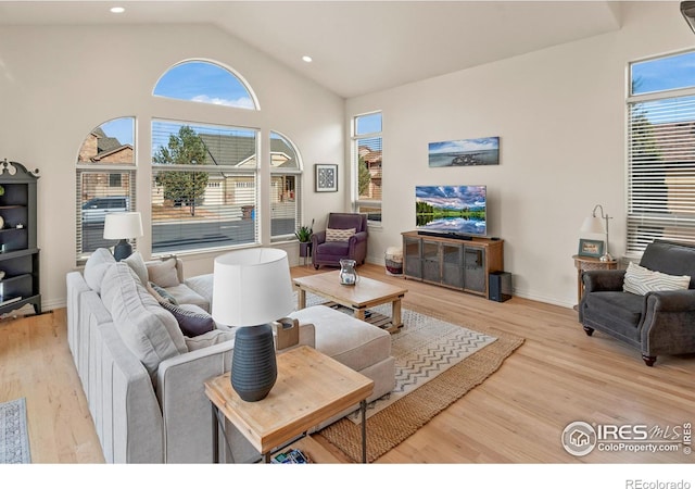 living room with a wealth of natural light, light hardwood / wood-style flooring, and high vaulted ceiling