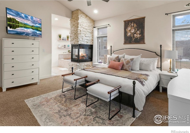 bedroom featuring a stone fireplace and vaulted ceiling