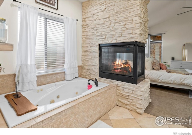 bathroom featuring tile patterned flooring, tiled tub, lofted ceiling, and a multi sided fireplace