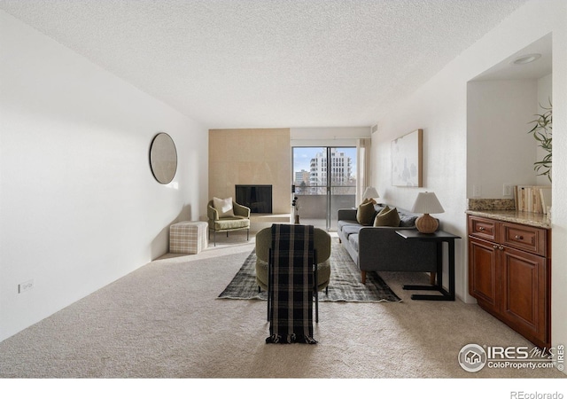 living room with a fireplace, light colored carpet, and a textured ceiling