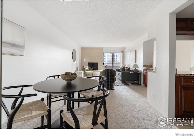 dining space featuring light colored carpet and a textured ceiling