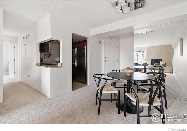 dining space featuring light colored carpet and a textured ceiling