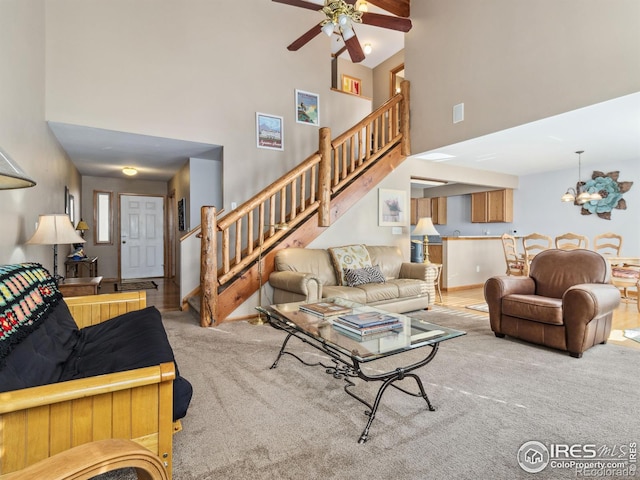 carpeted living room featuring a towering ceiling and ceiling fan with notable chandelier